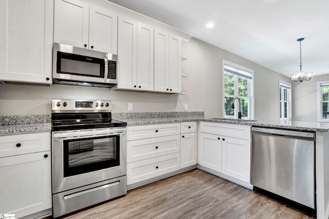 kitchen featuring light stone counters, a sink, white cabinetry, appliances with stainless steel finishes, and open shelves