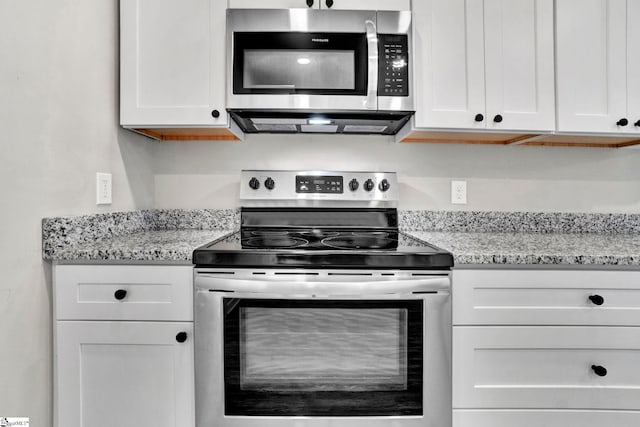 kitchen with light stone countertops, white cabinetry, and appliances with stainless steel finishes