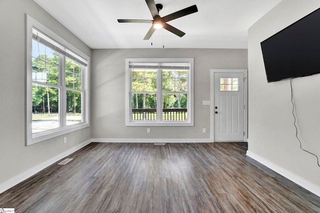 unfurnished living room featuring visible vents, dark wood-style flooring, a wealth of natural light, and baseboards