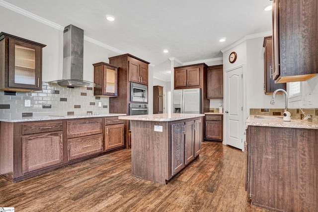 kitchen with appliances with stainless steel finishes, a center island, wall chimney exhaust hood, dark wood finished floors, and crown molding