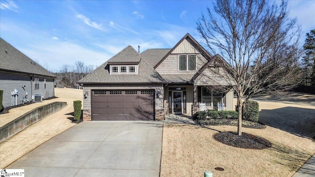 view of front of home with a shingled roof, covered porch, an attached garage, stone siding, and driveway