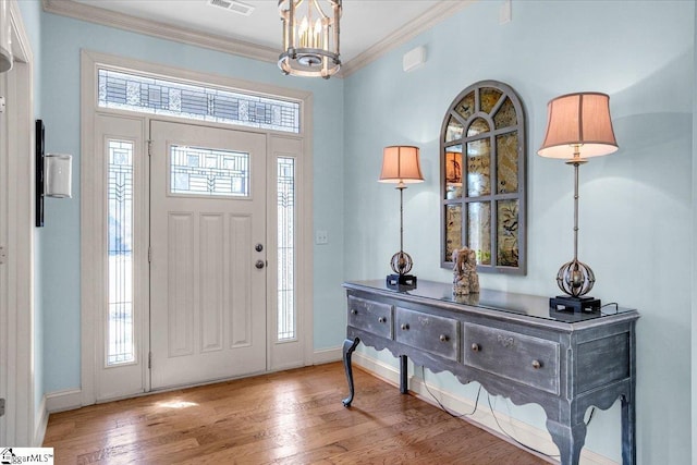 entryway featuring ornamental molding, wood-type flooring, visible vents, and baseboards