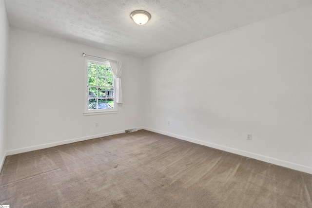 carpeted empty room featuring visible vents, baseboards, and a textured ceiling