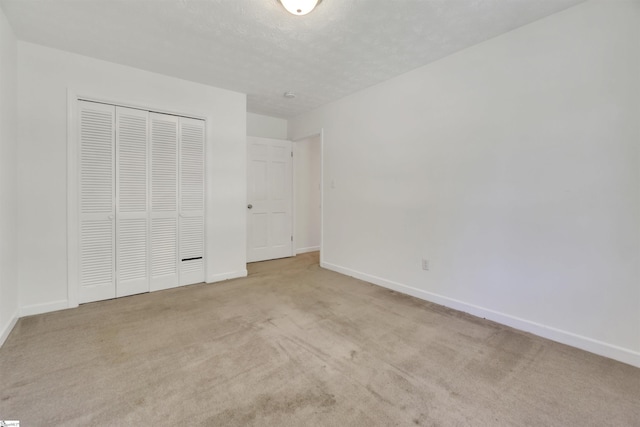 unfurnished bedroom featuring a closet, light colored carpet, and baseboards