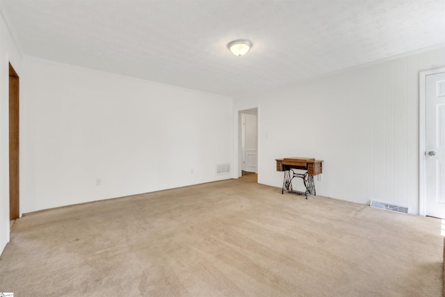 unfurnished room featuring visible vents, crown molding, and light colored carpet