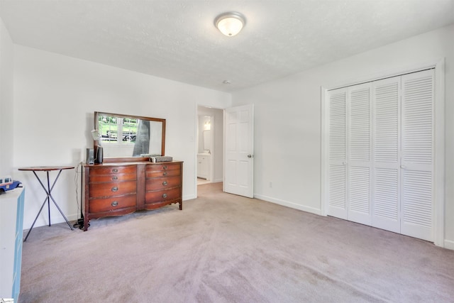 bedroom featuring a closet, light carpet, a textured ceiling, and baseboards