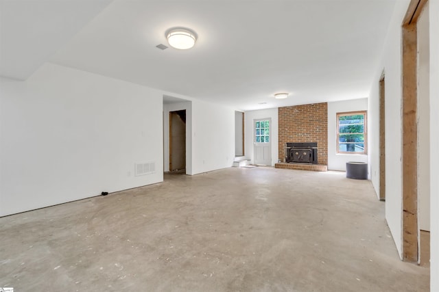 unfurnished living room with a brick fireplace, visible vents, and unfinished concrete floors