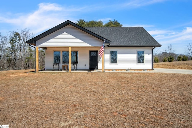 view of front facade featuring covered porch, a front lawn, and roof with shingles