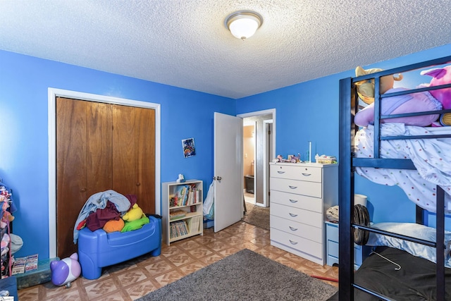 bedroom with light floors, a textured ceiling, and a closet