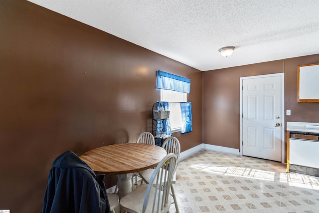 dining room featuring a textured ceiling and baseboards