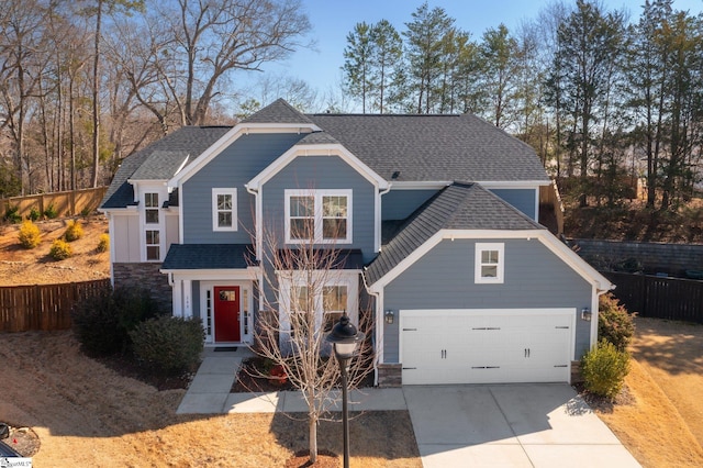 view of front of home with a shingled roof, concrete driveway, an attached garage, fence, and stone siding