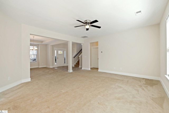 unfurnished room with baseboards, visible vents, light colored carpet, stairway, and ceiling fan with notable chandelier