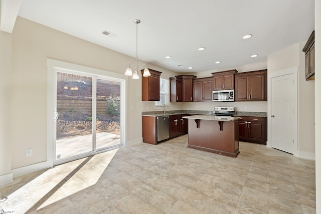 kitchen featuring a breakfast bar, decorative light fixtures, stainless steel appliances, light countertops, and recessed lighting