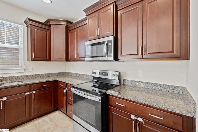 kitchen with appliances with stainless steel finishes, a sink, and light stone counters