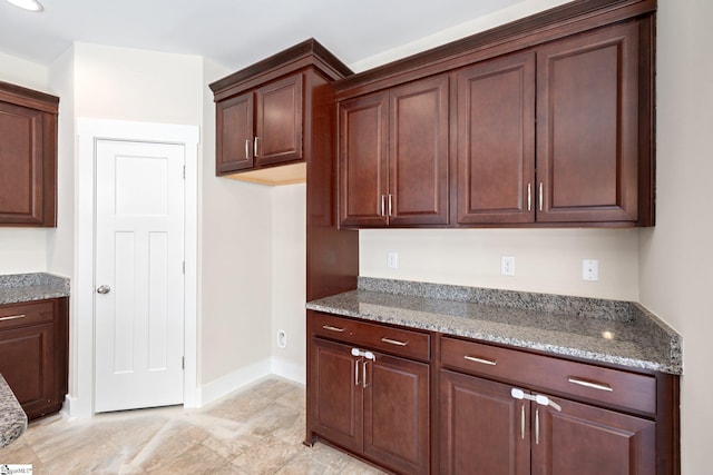 kitchen featuring light stone counters and baseboards