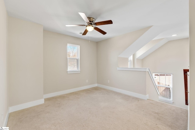 empty room with a ceiling fan, light carpet, and baseboards