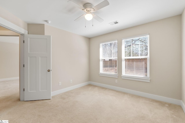 unfurnished room featuring light carpet, a ceiling fan, visible vents, and baseboards