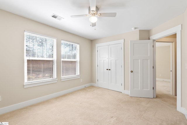 unfurnished bedroom with baseboards, visible vents, light colored carpet, ceiling fan, and a closet