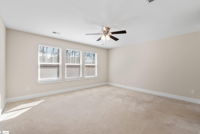 spare room featuring baseboards, ceiling fan, visible vents, and light colored carpet