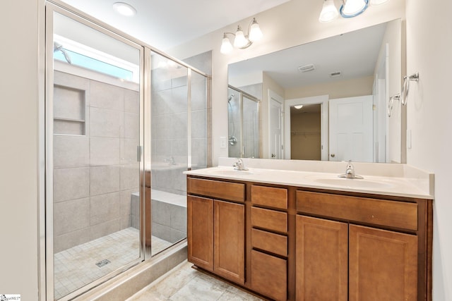 bathroom with double vanity, a shower stall, a walk in closet, and a sink