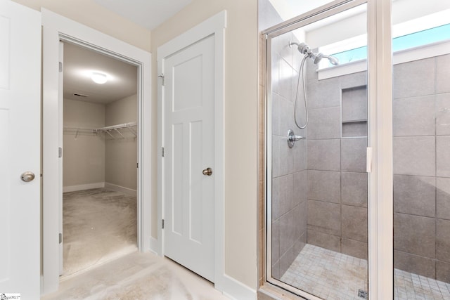 bathroom with baseboards, a spacious closet, and a shower stall