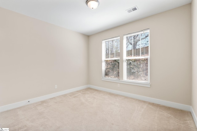 empty room featuring light carpet, baseboards, and visible vents