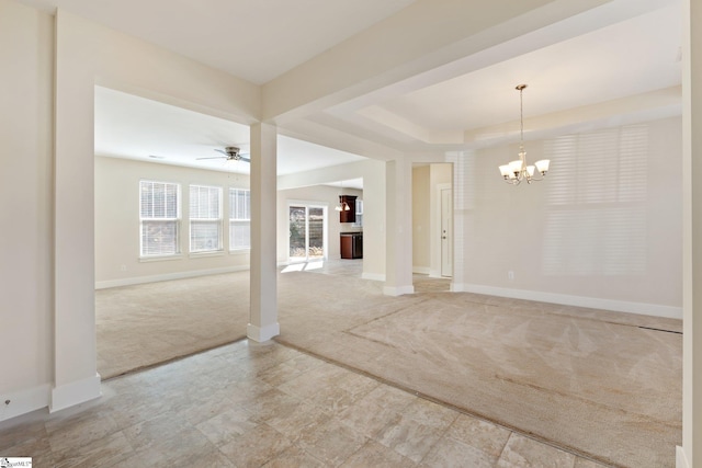 carpeted empty room with a raised ceiling, baseboards, and ceiling fan with notable chandelier