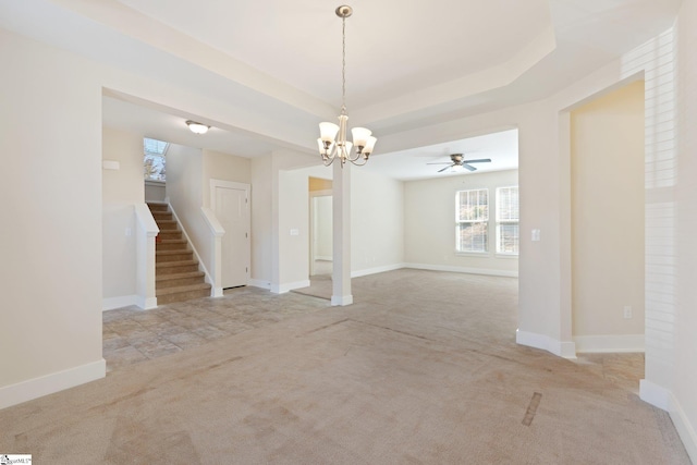 interior space with a raised ceiling, light colored carpet, stairway, an inviting chandelier, and baseboards