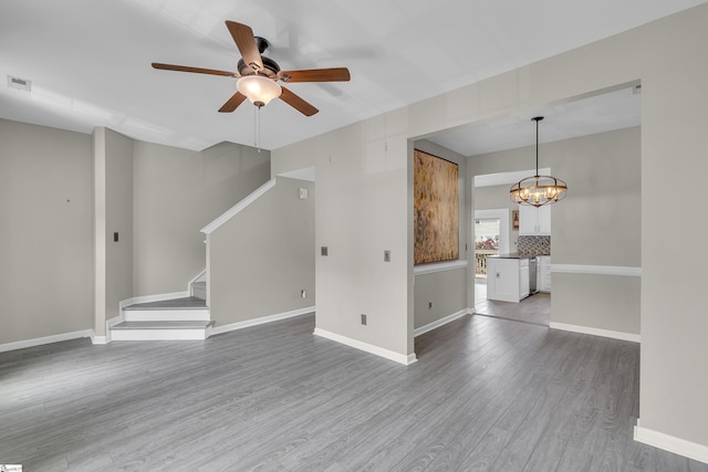 unfurnished living room with stairs, baseboards, and wood finished floors