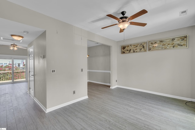 unfurnished room with ceiling fan, wood finished floors, visible vents, and baseboards