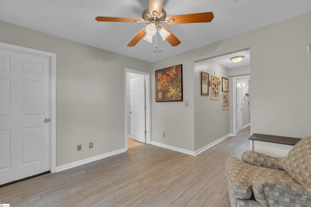 sitting room featuring ceiling fan, light wood-style flooring, and baseboards