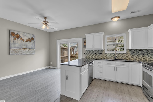 kitchen with dark countertops, visible vents, appliances with stainless steel finishes, white cabinetry, and a sink