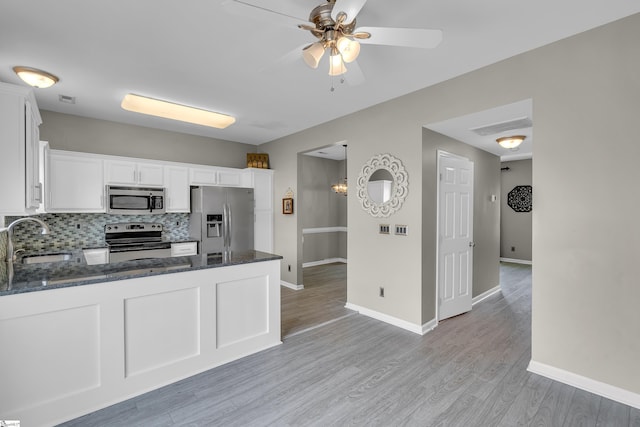 kitchen featuring stainless steel appliances, a peninsula, a sink, and white cabinetry