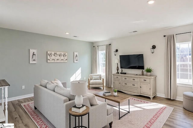 living area with light wood finished floors, visible vents, and a healthy amount of sunlight