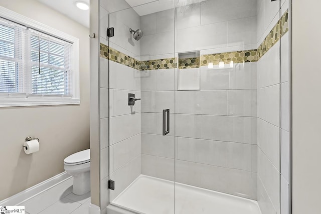 bathroom featuring toilet, a shower stall, baseboards, and tile patterned floors