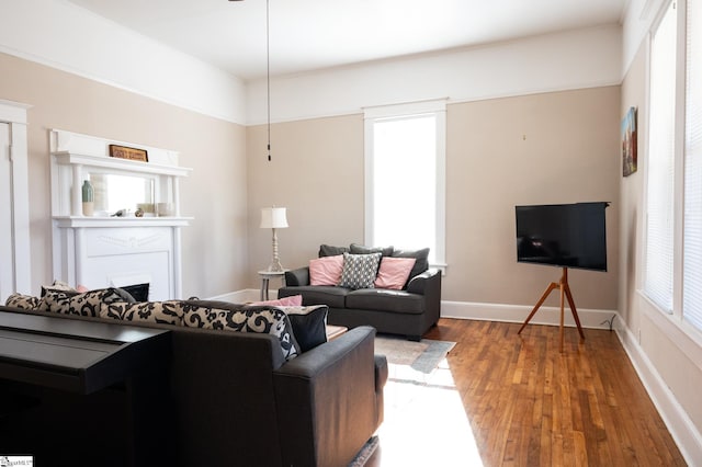 living room featuring a fireplace, baseboards, and wood finished floors