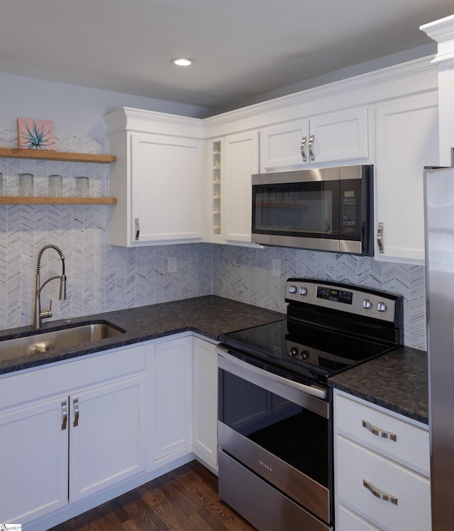 kitchen with decorative backsplash, white cabinets, appliances with stainless steel finishes, open shelves, and a sink