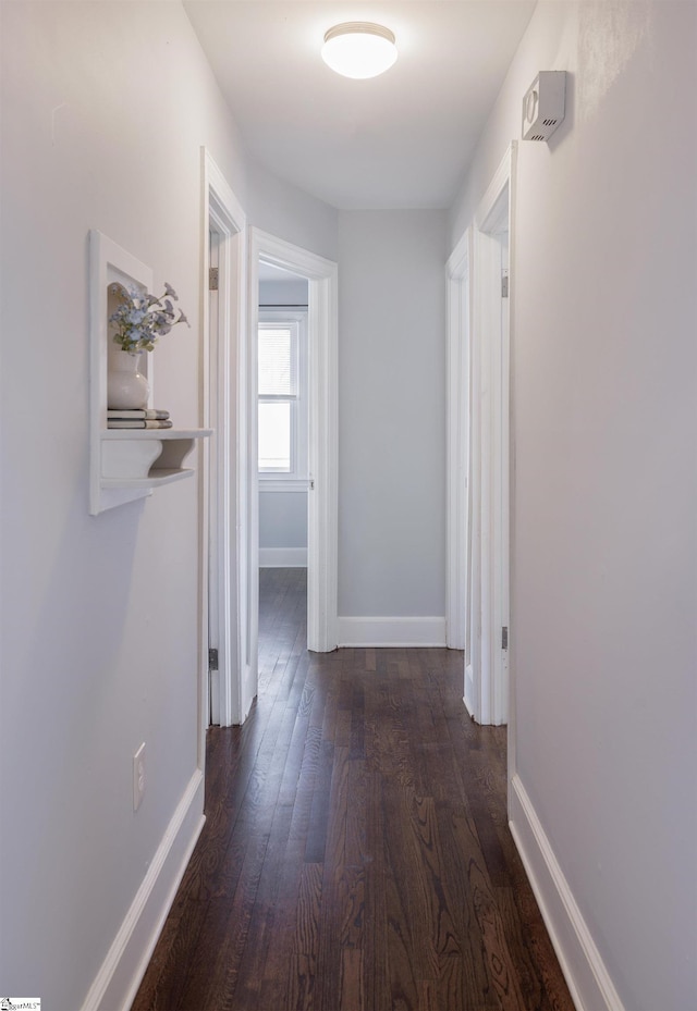 hall featuring dark wood-style floors and baseboards