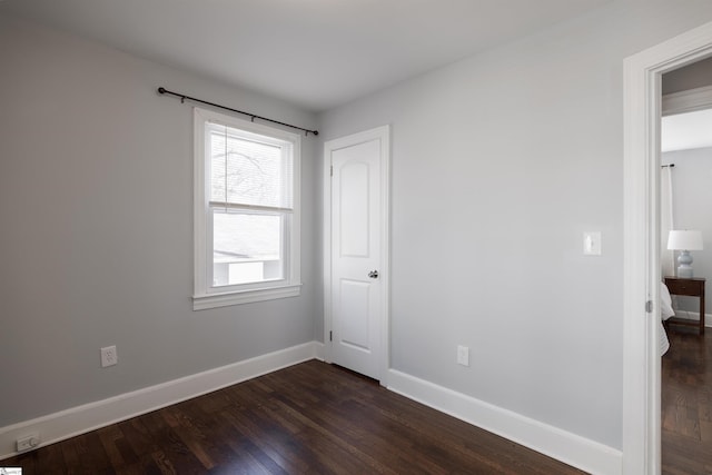 unfurnished bedroom with baseboards and dark wood-type flooring