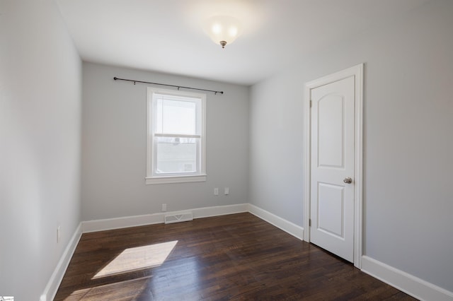 spare room with dark wood-style floors, baseboards, and visible vents