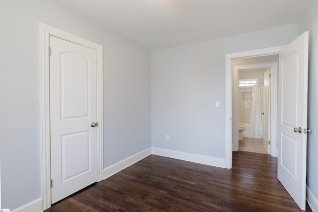 empty room featuring dark wood-type flooring and baseboards