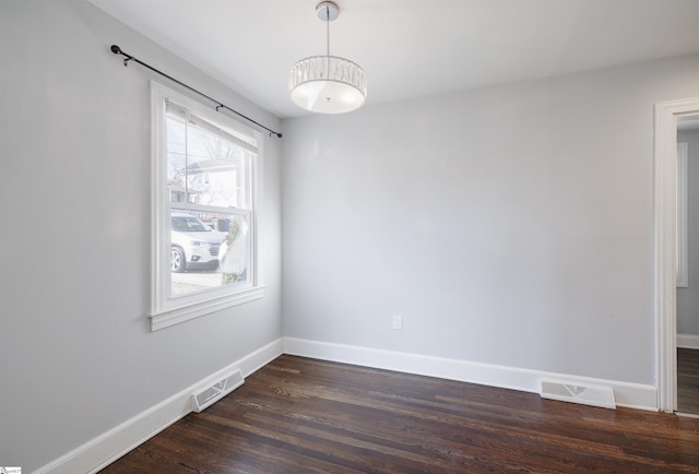 spare room with visible vents, dark wood finished floors, and baseboards