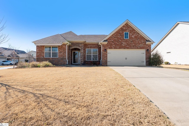 view of front of property featuring a garage, a front yard, concrete driveway, and brick siding