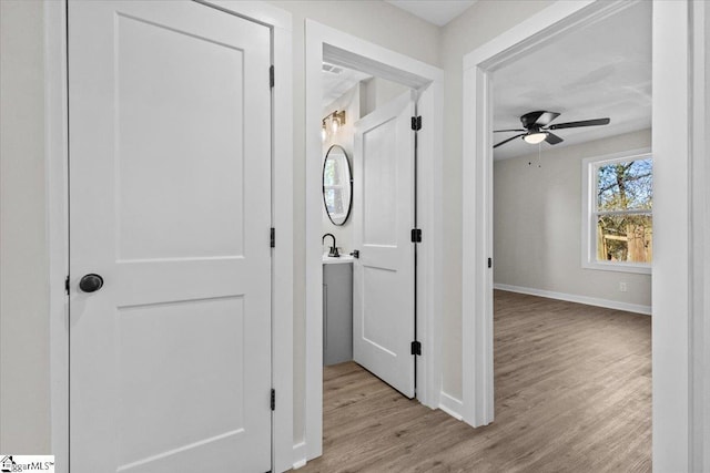 corridor featuring baseboards and light wood-style floors