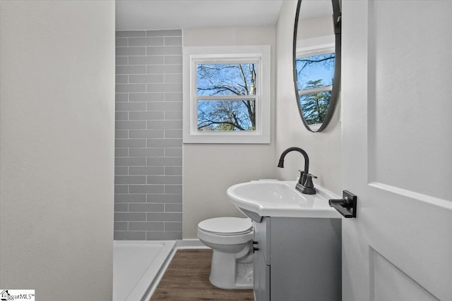 bathroom featuring wood finished floors, a shower stall, toilet, and vanity