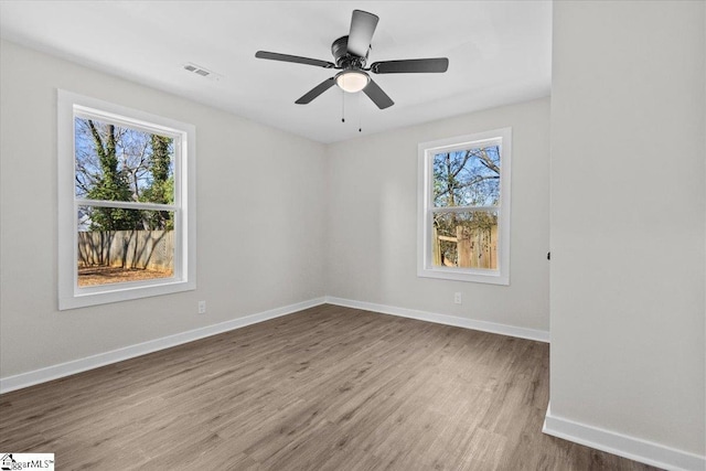 empty room with a healthy amount of sunlight, visible vents, baseboards, and wood finished floors