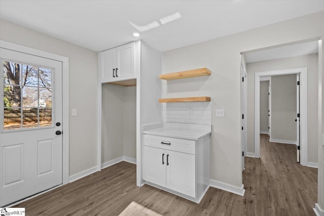 kitchen with dark wood-style flooring, open shelves, light countertops, backsplash, and white cabinetry