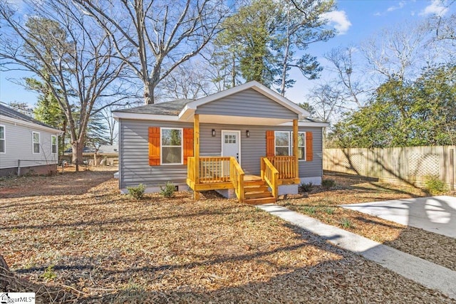 bungalow-style home with covered porch and fence