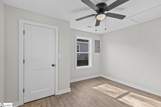 spare room featuring light wood finished floors, attic access, electric panel, visible vents, and baseboards