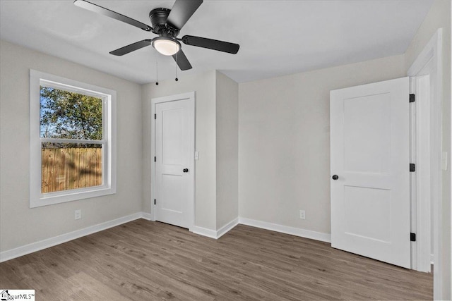 unfurnished bedroom with ceiling fan, wood finished floors, and baseboards